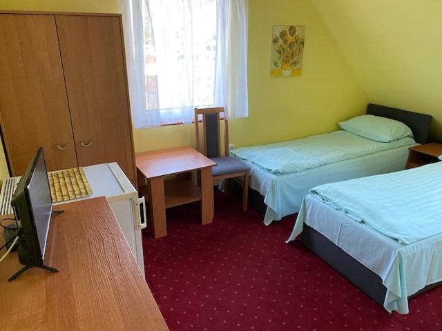 a room with two beds and a desk with a laptop at Domek 8 osobowy PORTOWA PRZYSTAŃ 150m od plaży in Mrzeżyno