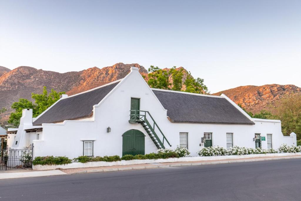 a white building with a black roof on a street at Klein Nektar Wine & Olive Estate in Montagu