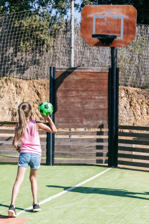 a young girl is hitting a ball at a basketball hoop at Camping Tucan - Mobile Homes by Lifestyle Holidays in Lloret de Mar