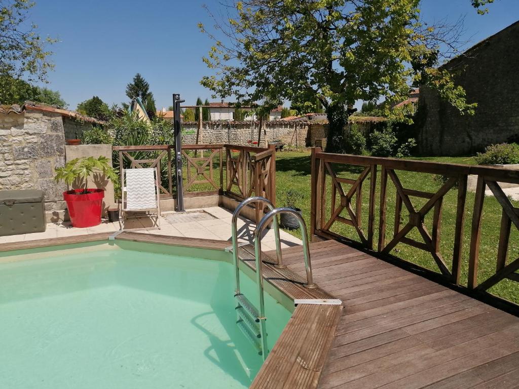 a swimming pool with a wooden fence and a wooden deck at Têtes à l'air in Montils