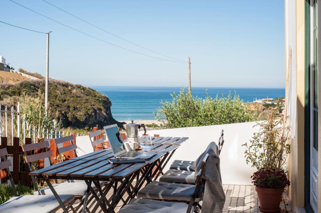 a table and chairs on a balcony with the ocean at Coworksurf - Villa dos Irmãos in Ericeira