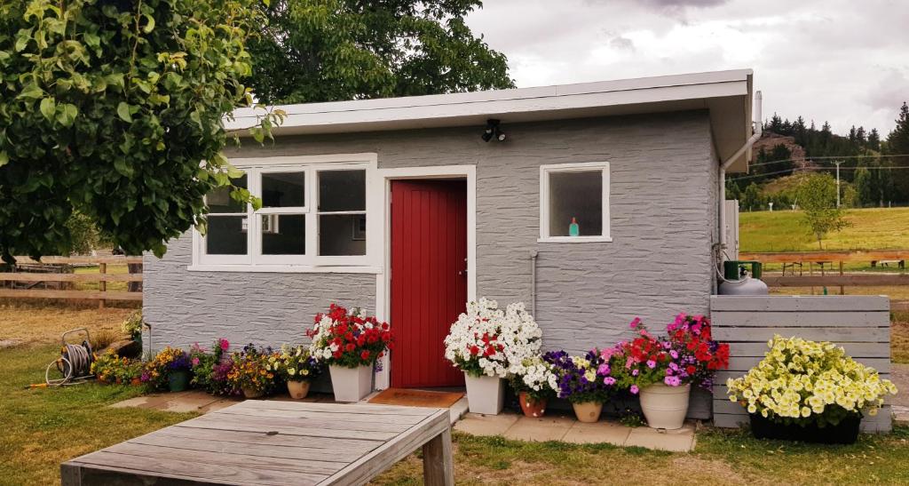 a tiny house with a red door and flowers at 'The Crib' on Legacy Vineyard in Alexandra