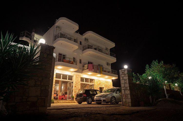 a building with cars parked in front of it at night at Vila Llaka in Himare