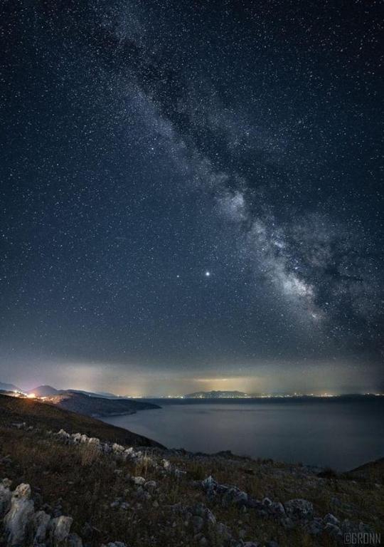 a starry night with the milky way over a lake at Vila Llaka in Himare