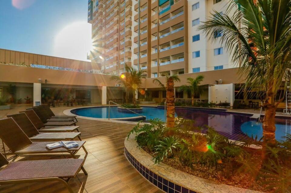 a hotel with a pool with lounge chairs and palm trees at Apto Master em Olímpia Park Resort in Olímpia