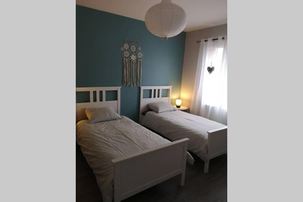 a bedroom with two beds and a window at Au cœur de la Sologne in Romorantin