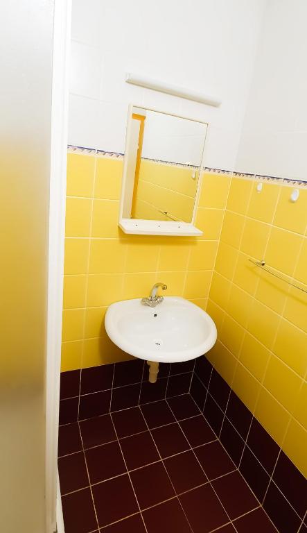 żółta łazienka z umywalką i lustrem w obiekcie Apartment Buco w mieście Starigrad-Paklenica
