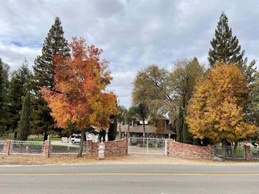einen Zaun mit zwei Bäumen vor einem Haus in der Unterkunft Kern River Home in Bakersfield