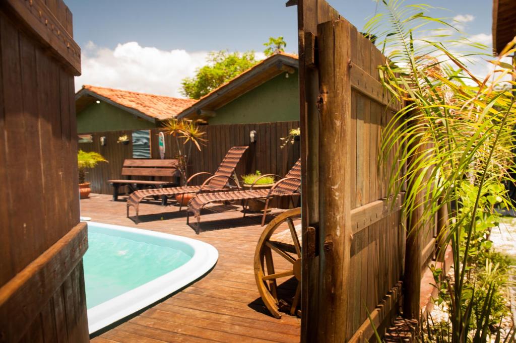 un patio trasero con piscina y una valla de madera en Cabanas Prema, en Praia do Rosa