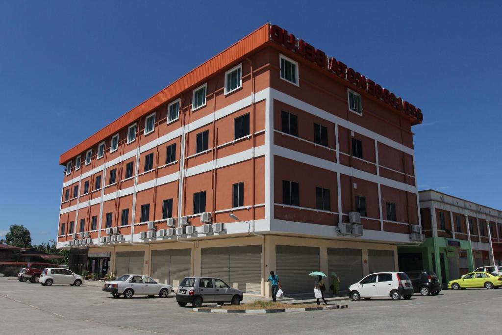 un gran edificio con coches estacionados en un estacionamiento en TD Lodge Kota Belud, en Kota Belud