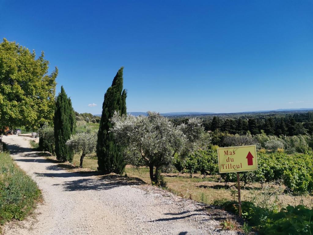 a sign on a dirt road with trees and a vineyard at Mas du Tilleul in Beaumes-de-Venise