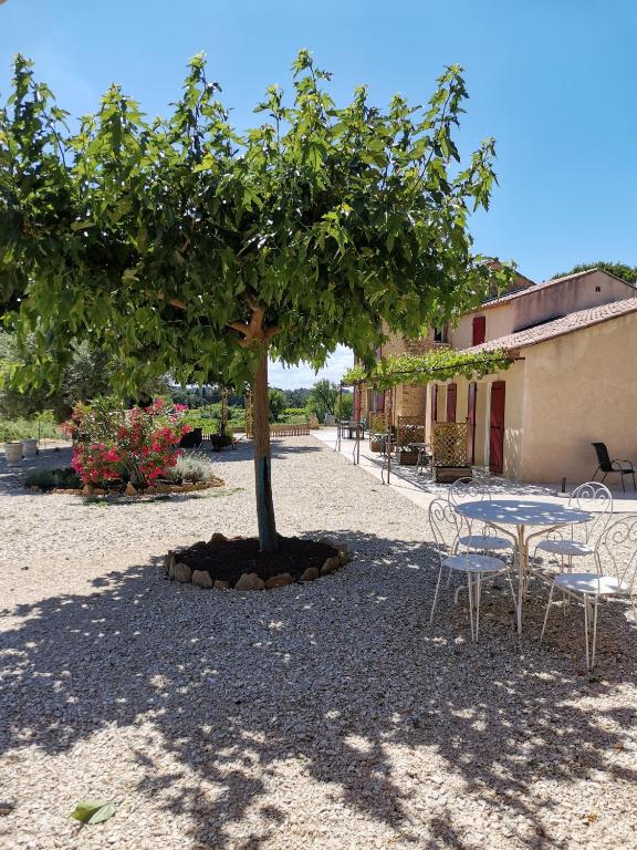 a table and chairs under a tree next to a building at Mas du Tilleul in Beaumes-de-Venise