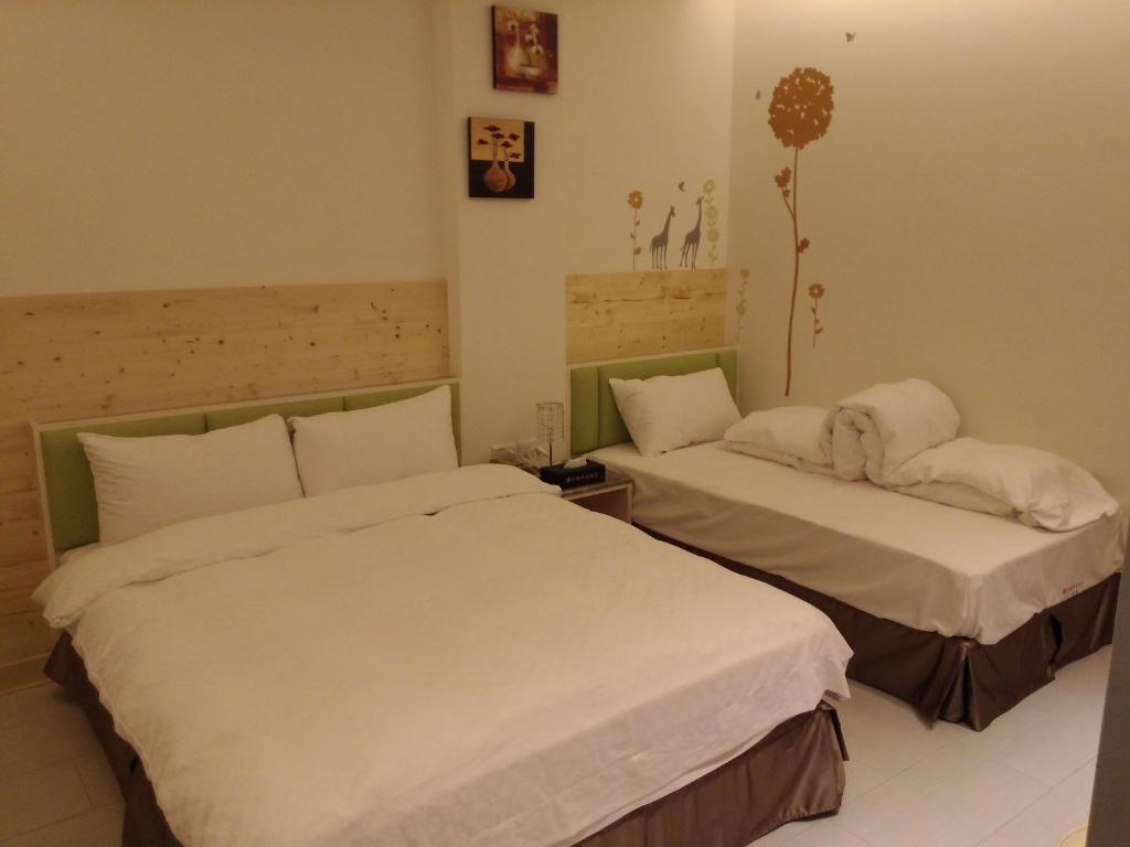 2 Betten in einem Hotelzimmer mit einem Hund, der darauf schläft in der Unterkunft Tilon Hotel in Pingtung