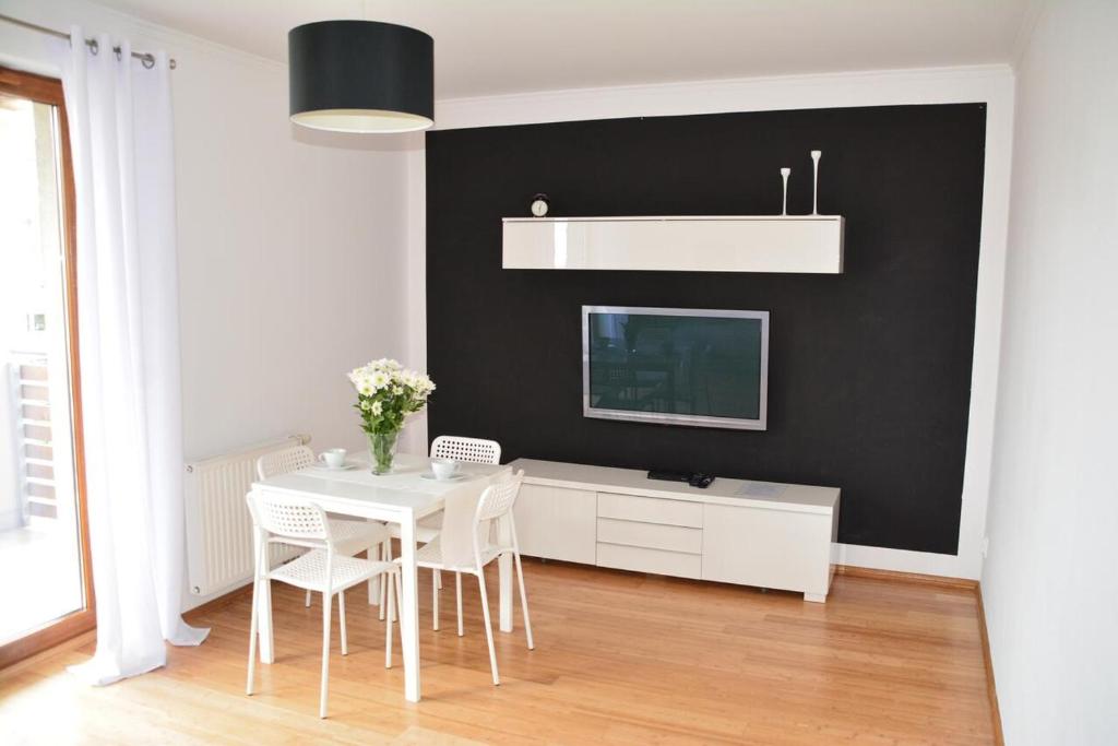 ein Esszimmer mit einem weißen Tisch und einer schwarzen Wand in der Unterkunft Apartament Black & White Wczasowa in Ustka