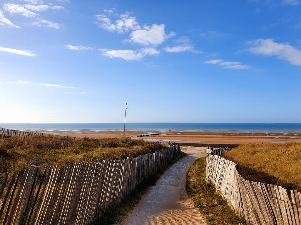 a wooden fence next to a beach with the ocean at Résidence Front de mer Cabourg - Accès direct plage in Cabourg