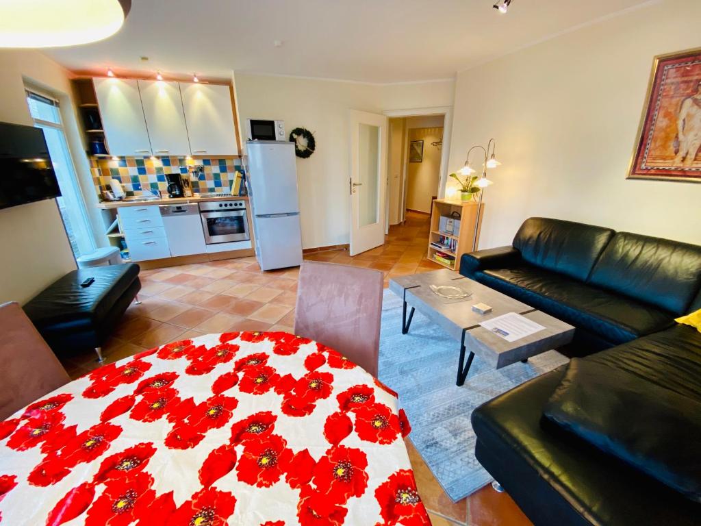 ein Wohnzimmer mit einem Tisch mit roten Blumen darauf in der Unterkunft Residenz Bleichröder - Ferienwohnung 11 in Heringsdorf