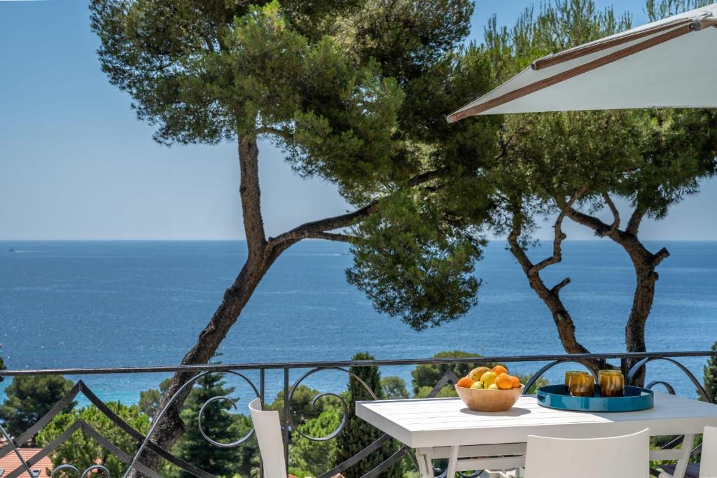 a table with a bowl of fruit on a balcony with the ocean at Appartement Mera Cosy apartment with incredible sea view in Èze