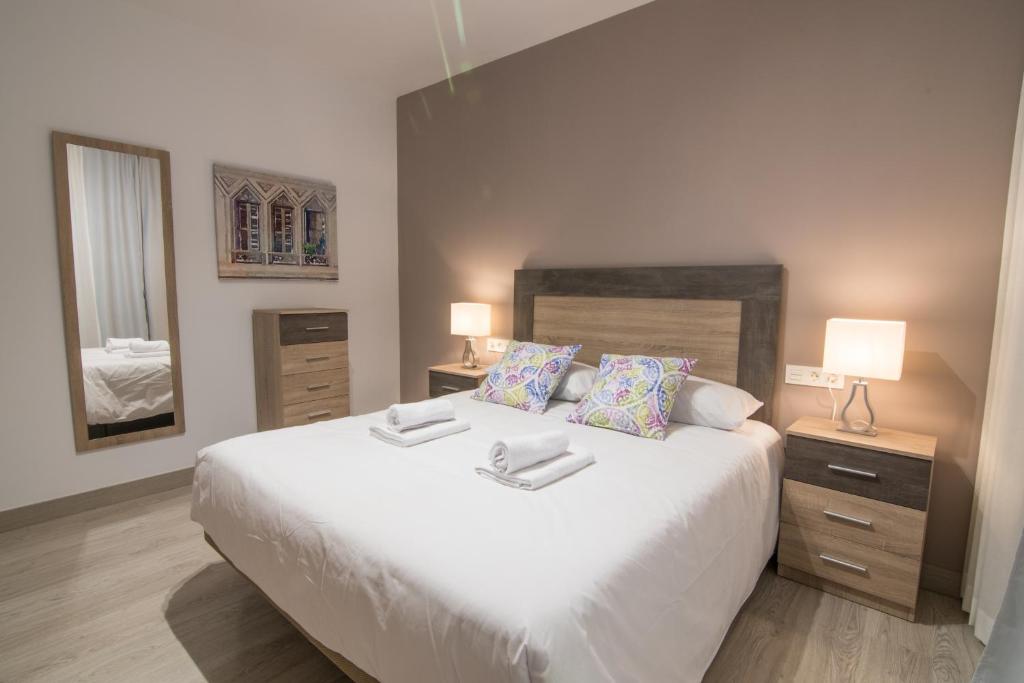 1 dormitorio con 1 cama blanca grande y 2 lámparas en tuGuest Station 2 apartment, en Granada