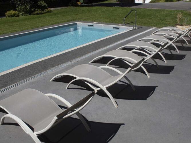 a row of white lounge chairs next to a swimming pool at Luxurious countryside holiday home with pool in Malmedy