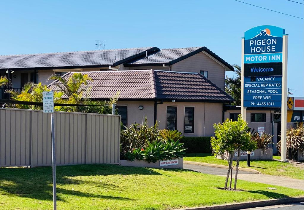a house with a sign in front of it at Pigeon House Motor Inn in Ulladulla