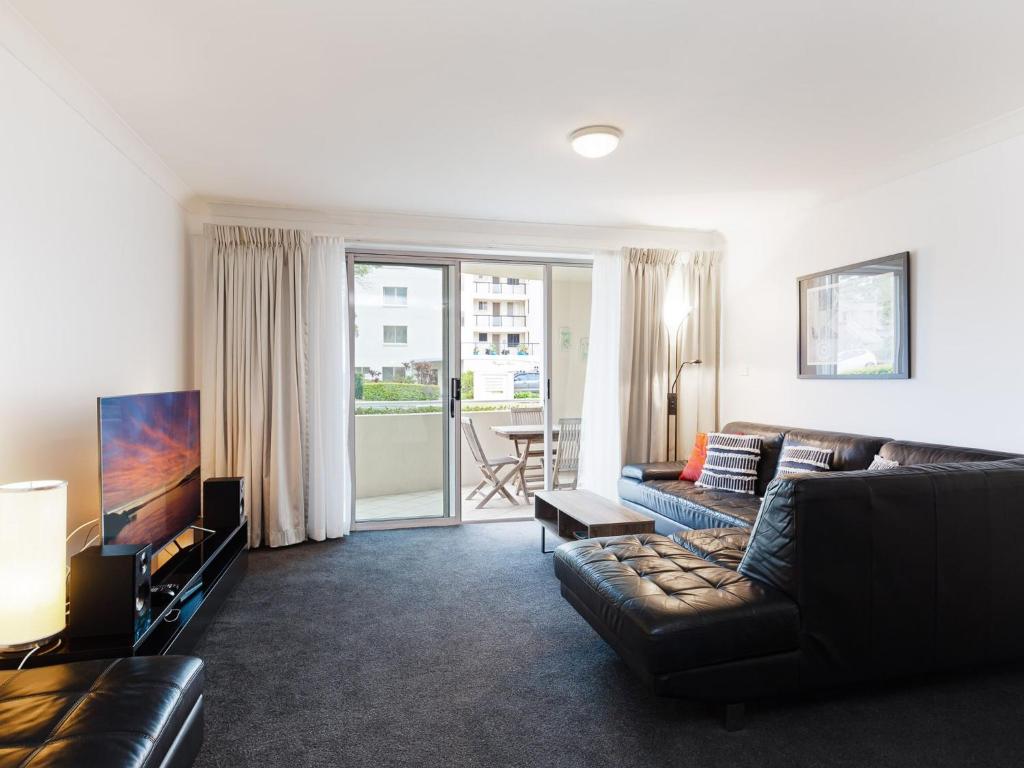 ein Wohnzimmer mit einem Sofa und einem TV in der Unterkunft Seashells, 1,21-23 Magnus Street - Unit with air con, wi-fi, complex pool and lift in Nelson Bay