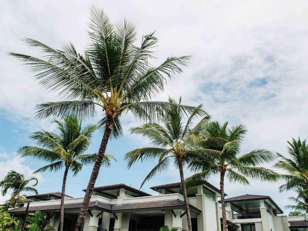 a group of palm trees in front of a building at Pullman Port Douglas Sea Temple Resort and Spa in Port Douglas