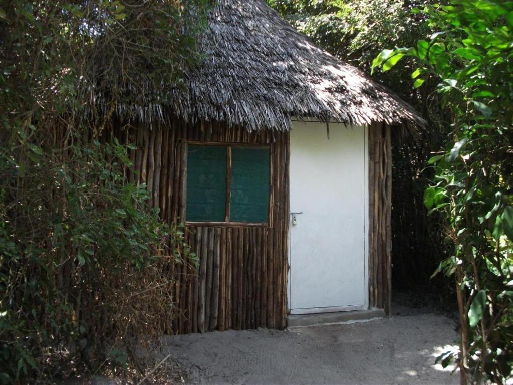 a small hut with a thatched roof and a white door at Room in BB - Mida Creek Eco Camp - relax in cosy cottage 