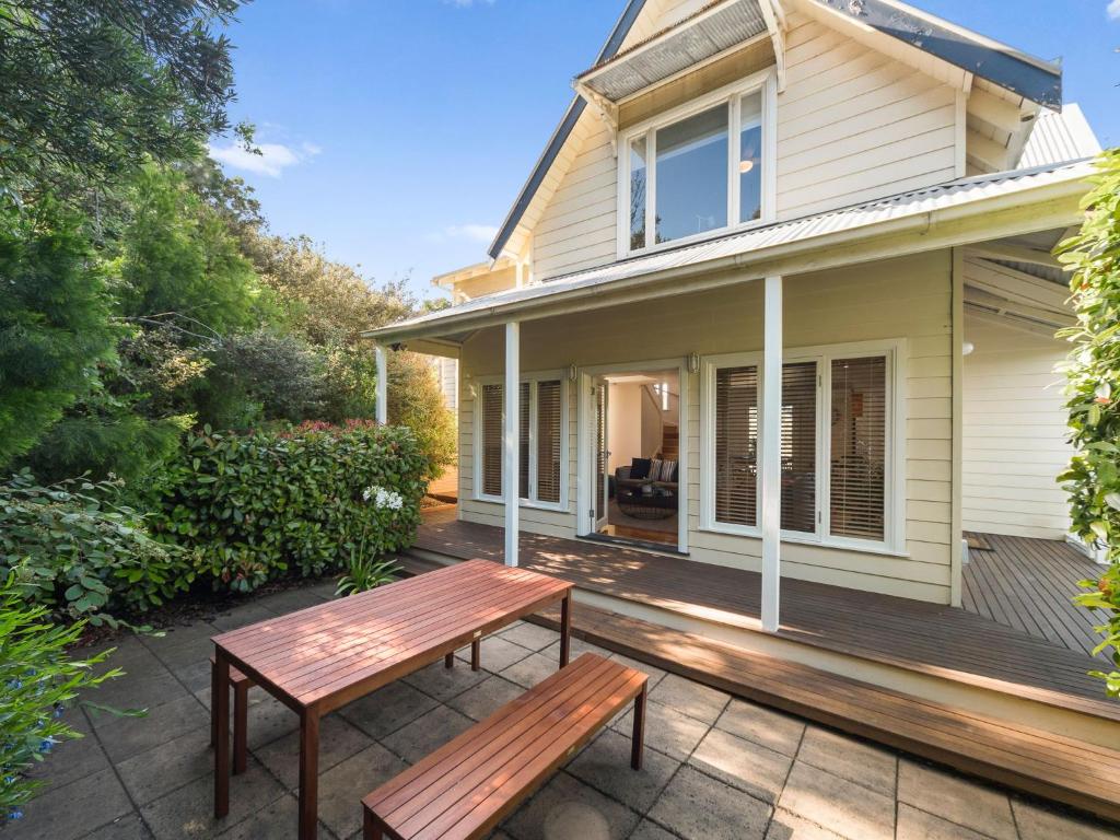 a patio with two benches in front of a house at Hamptons By The Bay in Rye