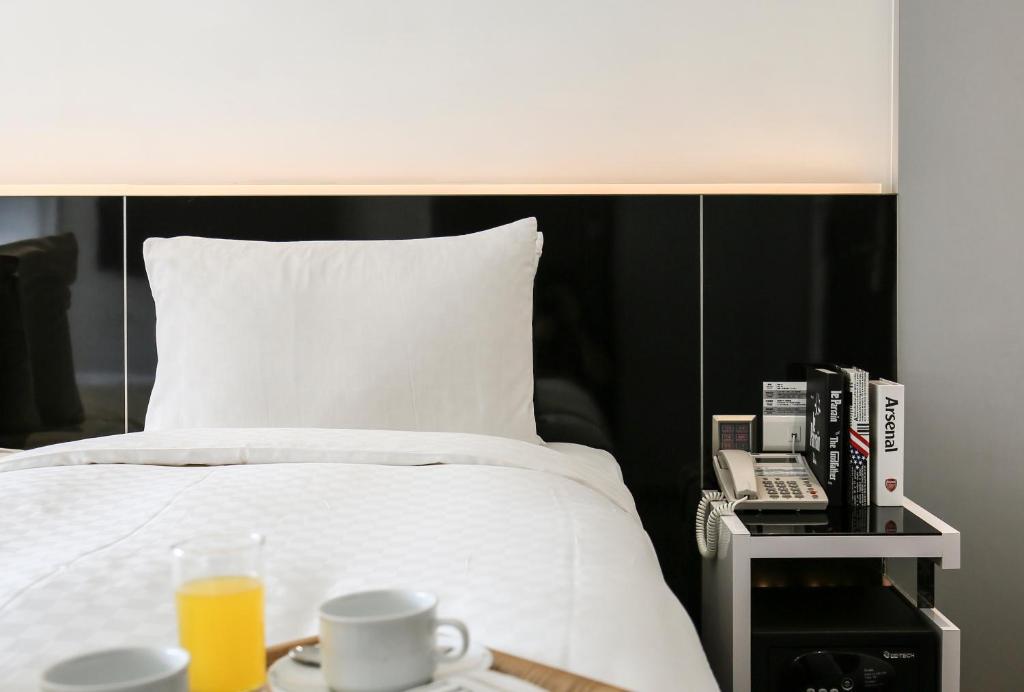 a bed with a black headboard and a table with a phone at CityInn Hotel Plus - Taichung Station Branch in Taichung