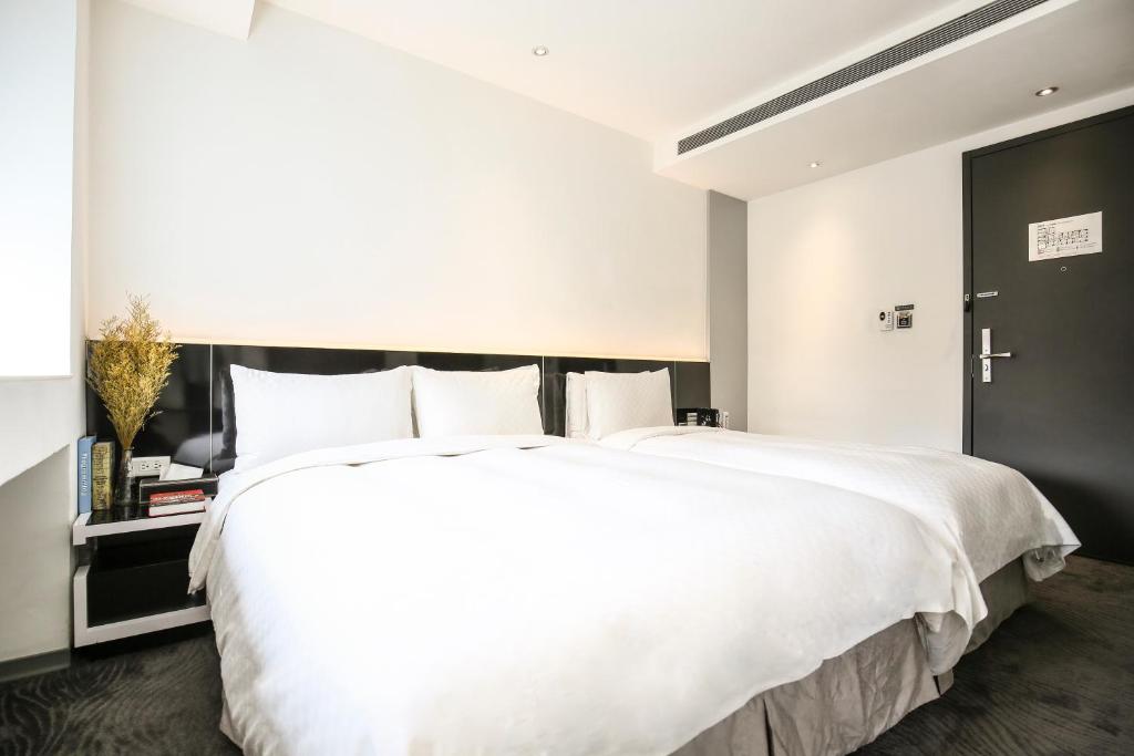 a bedroom with a large white bed and a black door at CityInn Hotel Plus - Taichung Station Branch in Taichung