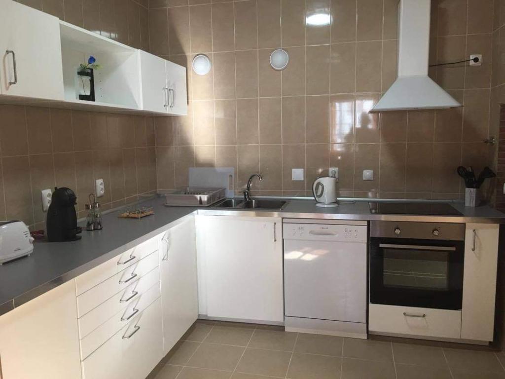 uma cozinha com armários brancos e um forno com placa de fogão em Casa do Avô Silva em Santa Cruz das Flores