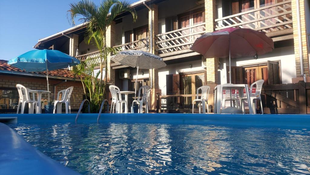 ein Resort mit einem Pool mit Stühlen und Sonnenschirmen in der Unterkunft Pousada Kauai in Praia do Rosa