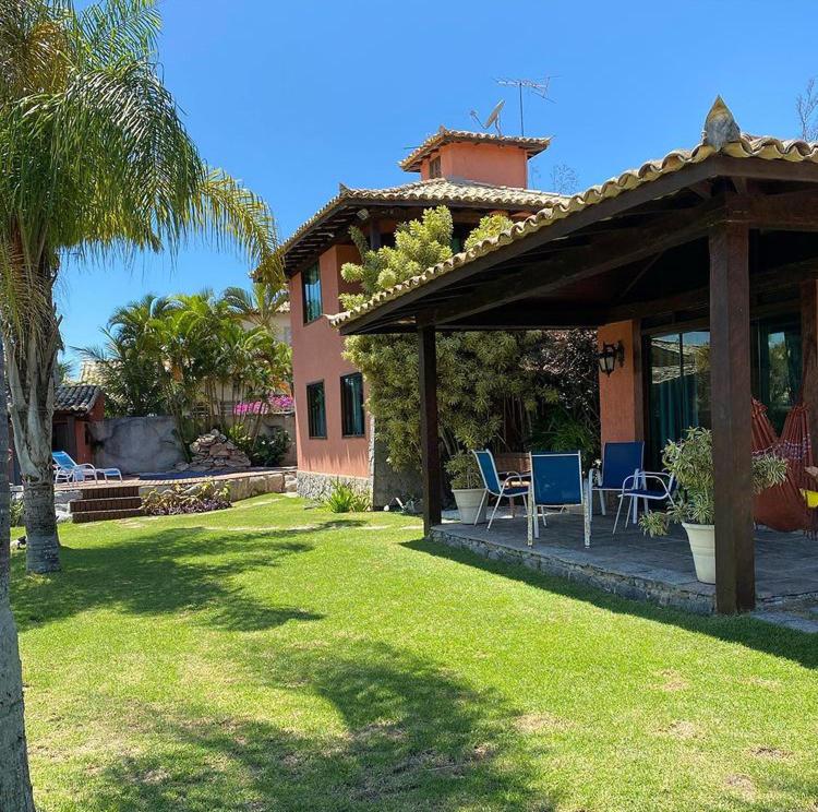 un patio con una casa con un patio y una palmera en Casa Buzios Geriba, en Búzios