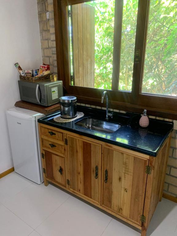 a kitchen counter with a sink and a window at Hostel Vale do Rosa in Praia do Rosa