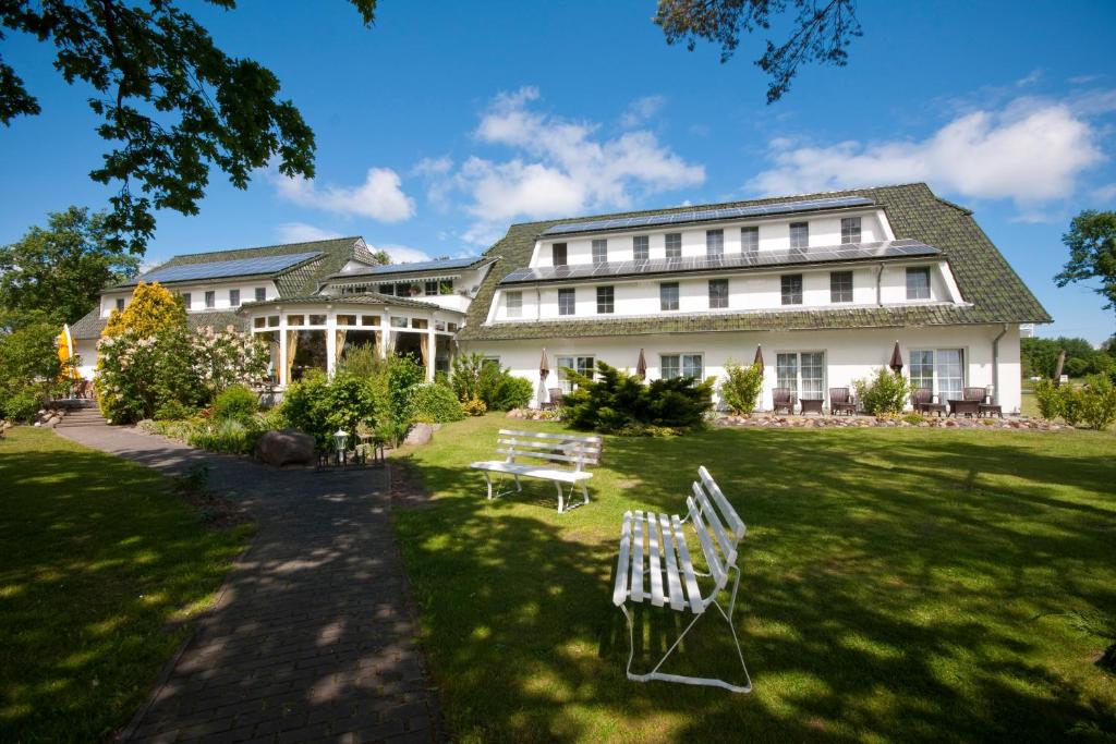 ein großes weißes Gebäude mit Stühlen im Gras in der Unterkunft Hotel-Marks-Garni in Zingst