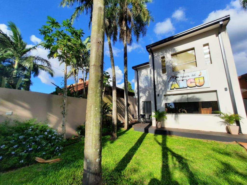 une maison avec des palmiers dans une cour dans l'établissement Posada del Angú, à Puerto Iguazú