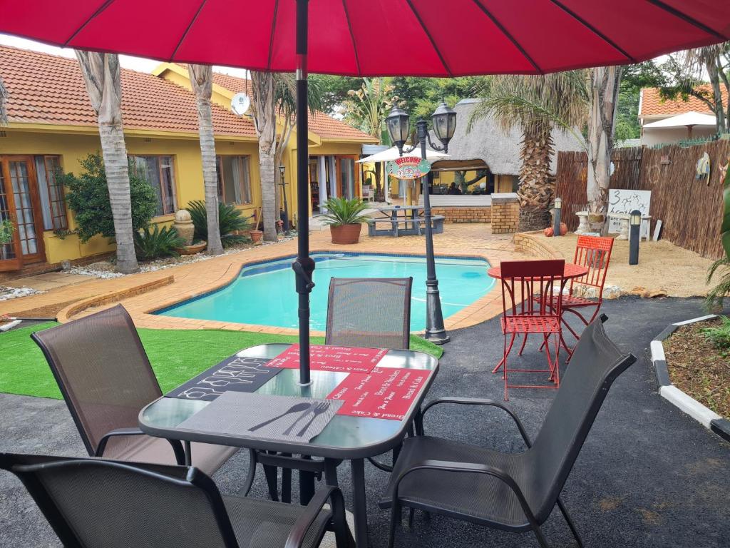un tavolo e sedie sotto un ombrellone accanto alla piscina di 3 Brothers B&B a Edenvale