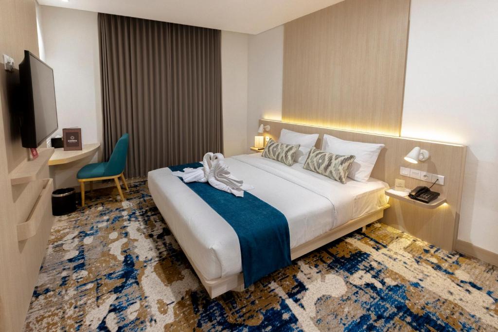 a hotel room with a bed and a tv at Cordia Hotel Yogyakarta - Hotel Dalam Bandara in Glagah