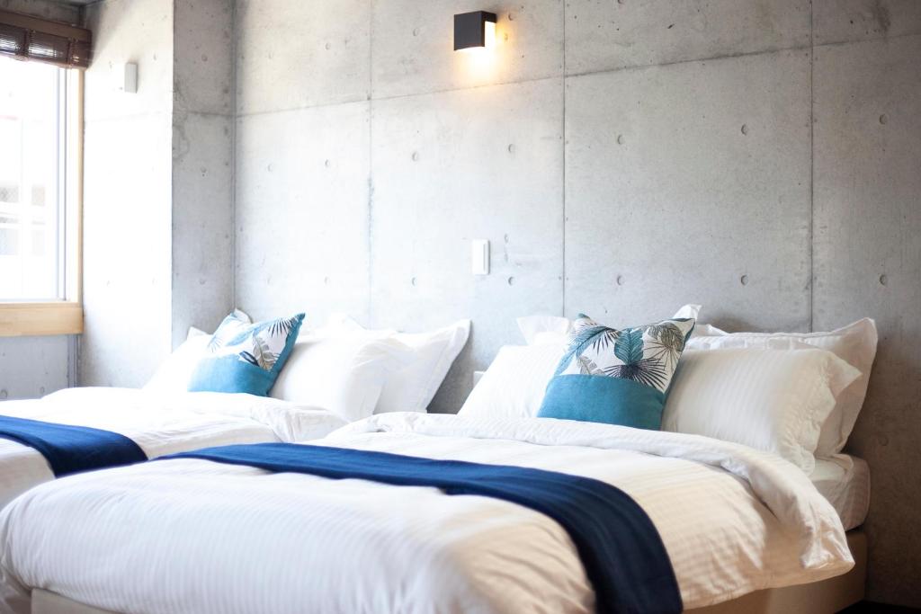 2 bedden in een kamer met witte lakens en blauwe kussens bij Kokusai Street Garden Hotel -SEVEN Hotels and Resorts- in Naha