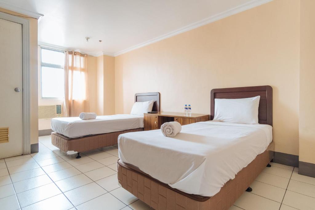 um quarto de hotel com duas camas e uma janela em Dechmark Hotel em Manila