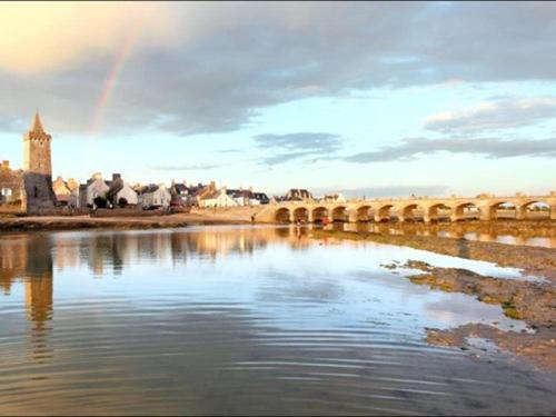 een brug over een rivier met een regenboog in de lucht bij Aux 13 Arches in Portbail