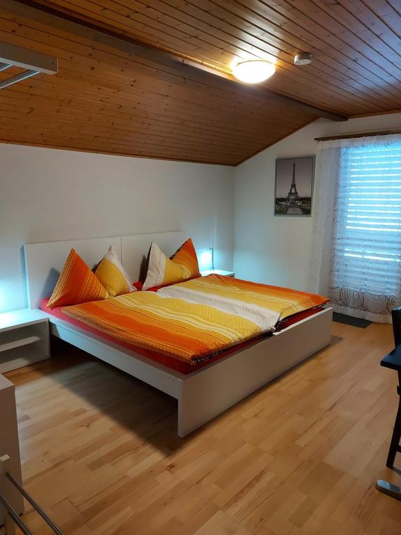 1 dormitorio con 1 cama con sábanas de color naranja y amarillo en good bed biberist en Biberist