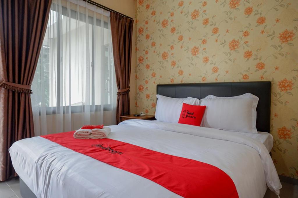 a bedroom with a large bed with red pillows at RedDoorz @ Jalan Majapahit Semarang in Alastuwo