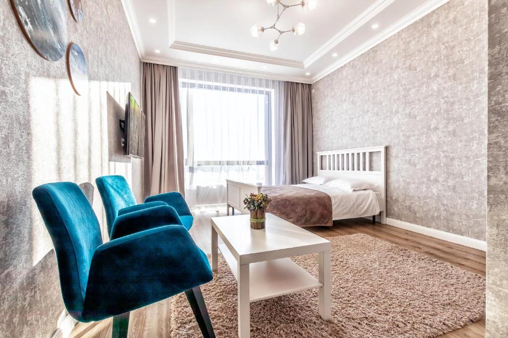 - une chambre avec un lit, des chaises bleues et une table dans l'établissement Raisson Ahotel B172, à Astana