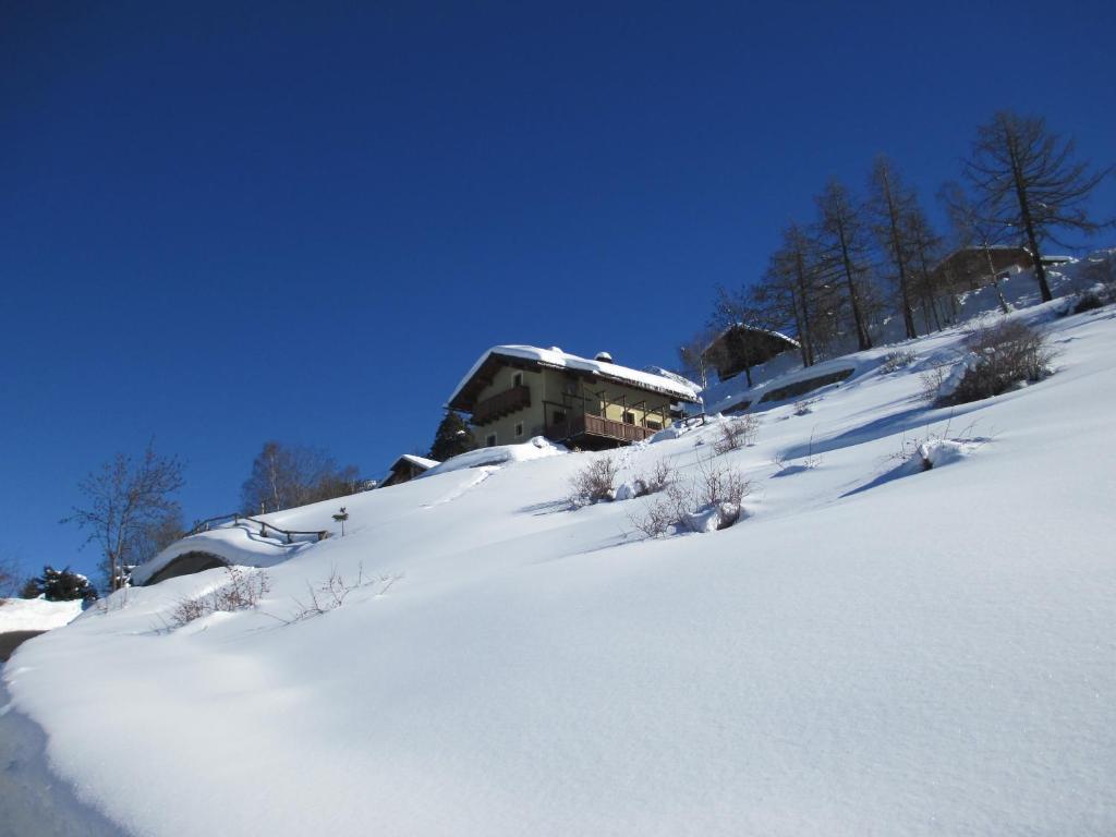 a snow covered hill with a building in the background at Petite Cerise in Gressan