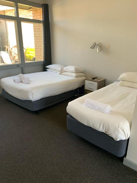 two beds in a room with a window at HOPETOUN COMMUNITY HOTEL MOTEL in Hopetoun