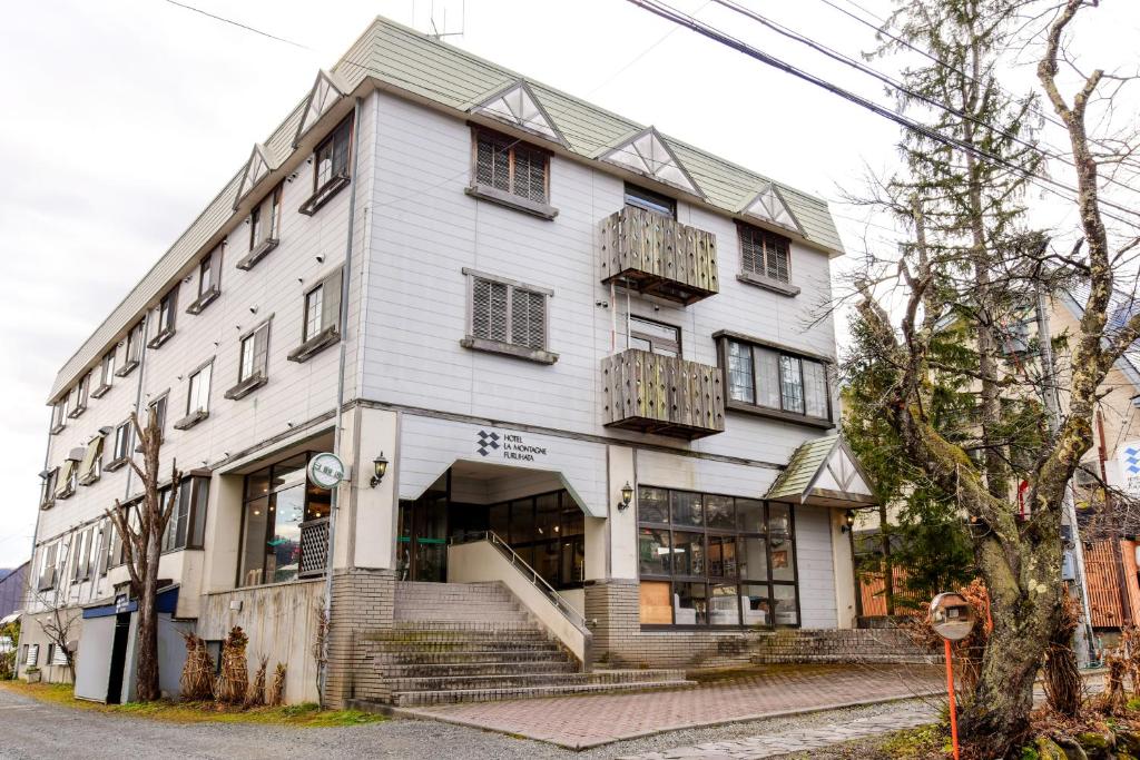 un edificio blanco con ventanas y balcones en una calle en Hotel La Montagne Furuhata, en Hakuba