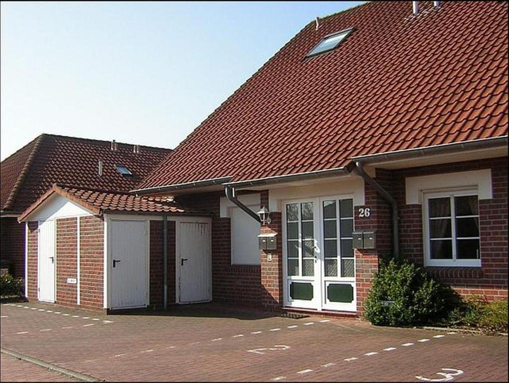 Maison en brique rouge avec 2 garages blancs dans l'établissement Ferienwohnung Wilde, à Hooksiel