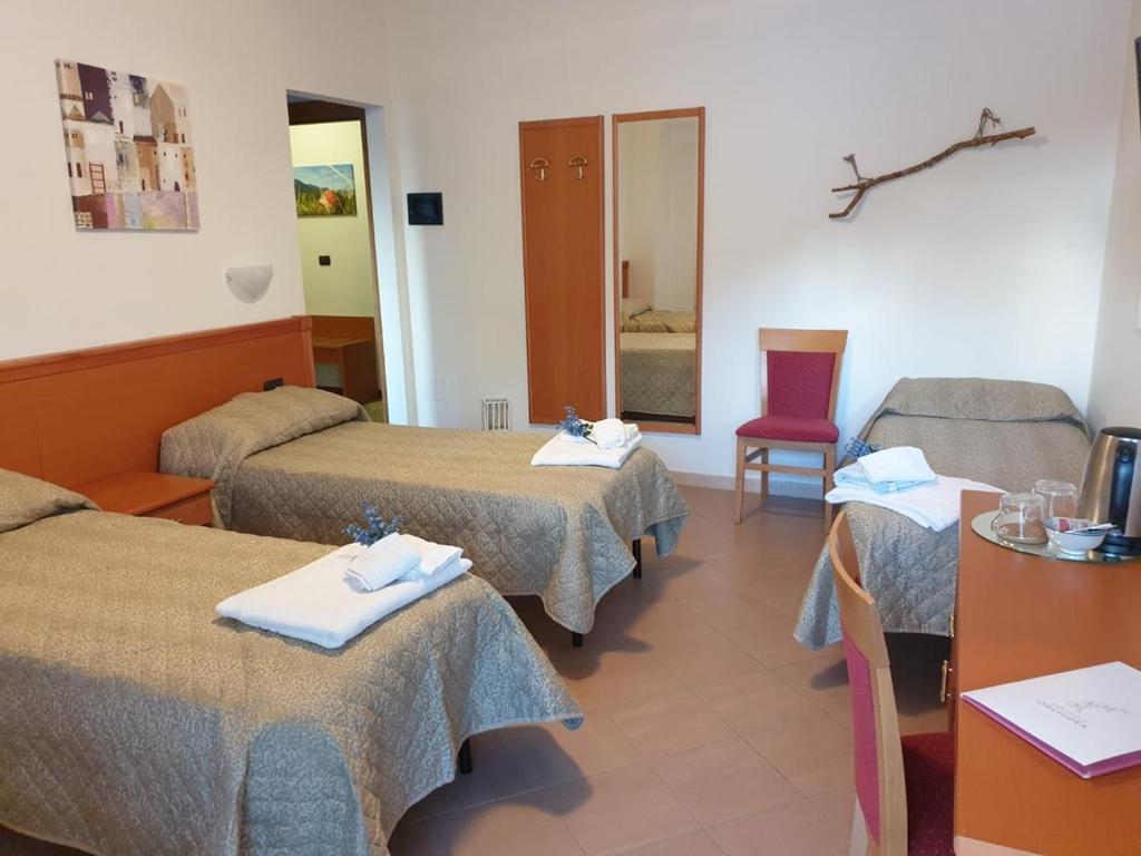 een hotelkamer met drie bedden en een tafel en stoelen bij Casa Vacanze Orchidea in Pinerolo