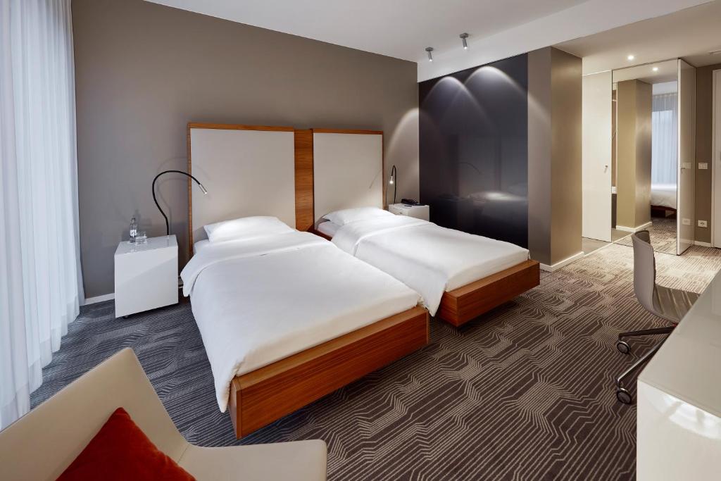 a hotel room with two beds and a mirror at LÉGÈRE HOTEL Luxembourg in Luxembourg